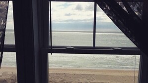 A view of a beach through a window with a view of the ocean and a sandy shore. - Misquamicut Beach Front Inn (Westerly)