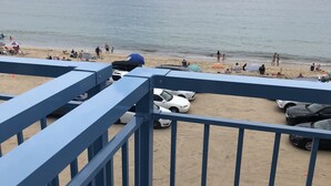 A beach with a blue railing, cars parked on the sand, and people enjoying the beach. - Misquamicut Beach Front Inn (Westerly)