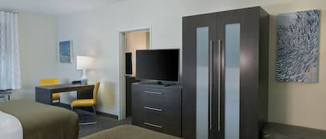 A hotel room with two beds, a desk with a chair, a television, a wardrobe, and artwork on the wall.