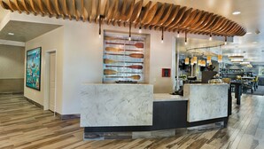 A reception area with a wooden ceiling design, a marble counter, and a wall-mounted artwork of wooden paddles. - Oxford Suites Bellingham (Bellingham)