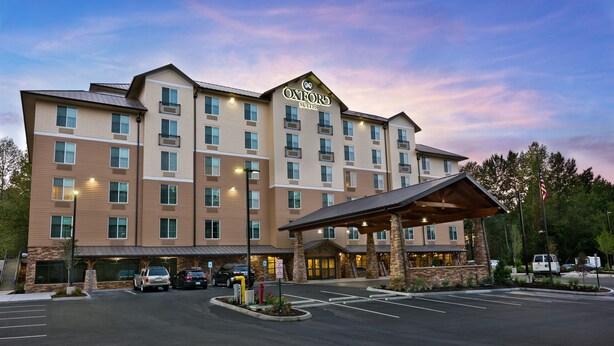 A multi-story hotel with a prominent entrance, a covered outdoor area, and a parking lot. - Oxford Suites Bellingham (Bellingham)