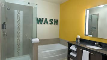 Un baño moderno con ducha de vidrio, bañera y lavamanos con espejo.
