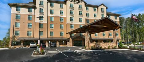 A multi-story hotel with a prominent entrance, a covered lobby area, and a parking lot.