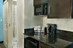 A kitchen with a microwave, coffee maker, and a coffee station with Starbucks cups.