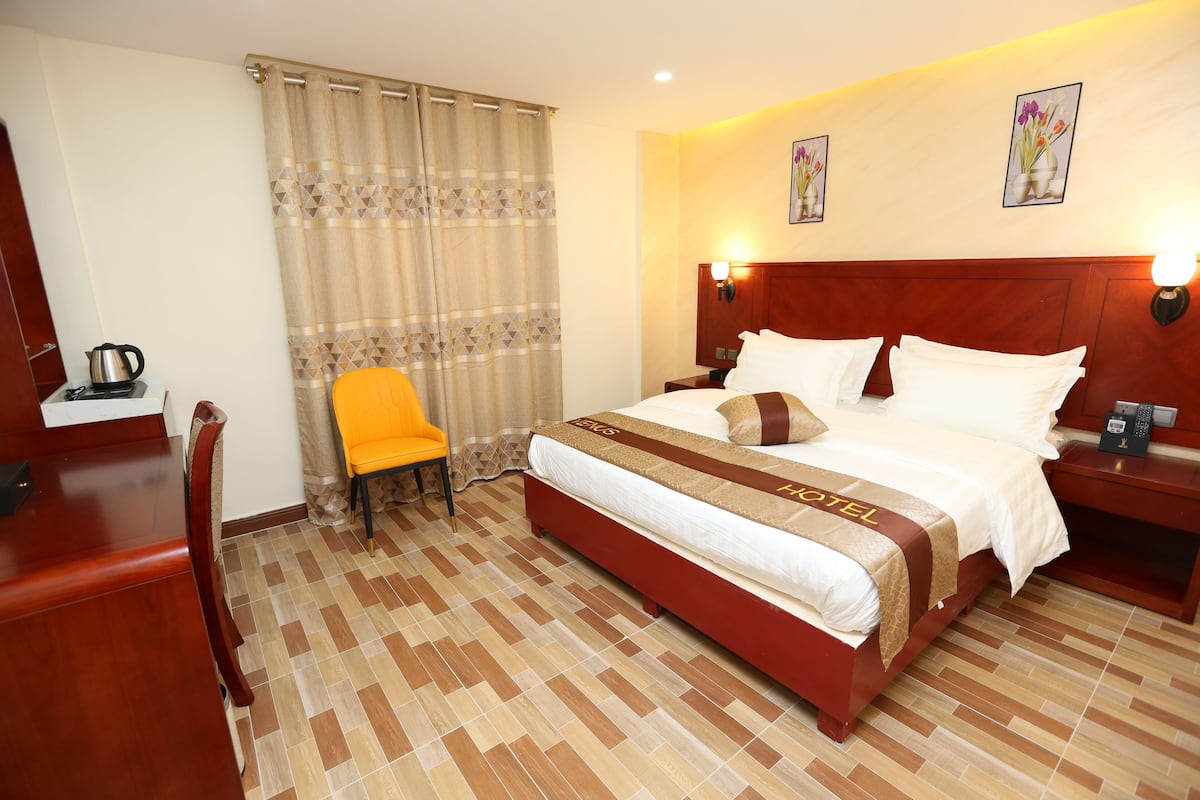 A hotel room with a bed, a chair, a desk, and a nightstand.