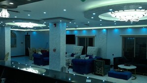 A modern living room with blue and white furniture, a chandelier, and a large window. - Petra Venus Hotel (Wadi Musa)