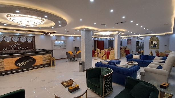 A hotel lobby with a reception desk, seating area, and a chandelier. - Petra Venus Hotel (Wadi Musa)