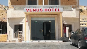 A multi-story building with a sign reading "VENUS HOTEL" at the entrance. - Petra Venus Hotel (Wadi Musa)