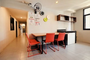 Une cuisine moderne avec un coin repas, comprenant une table avec des chaises, un ventilateur et divers objets fixés au mur.