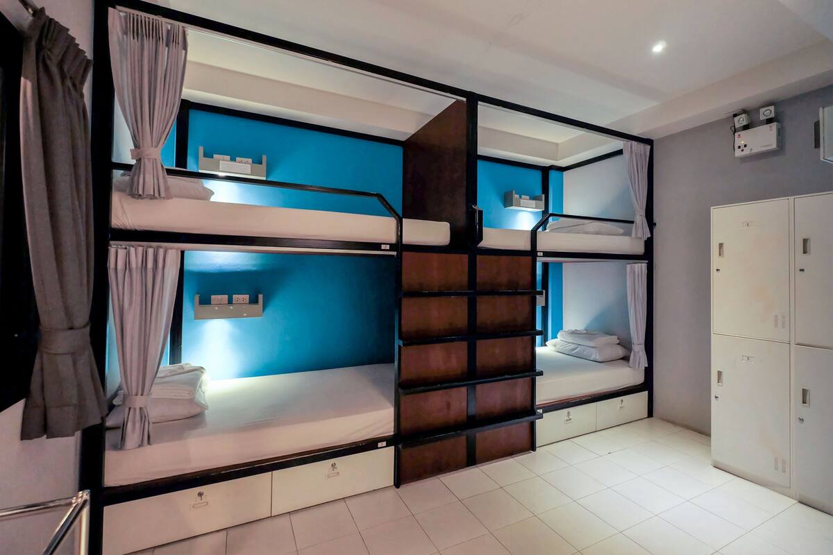 A dormitory room with bunk beds, a wardrobe, and a blue accent wall.