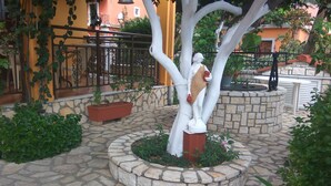 Un cortile con una statua, pavimento in pietra e piante in vaso.