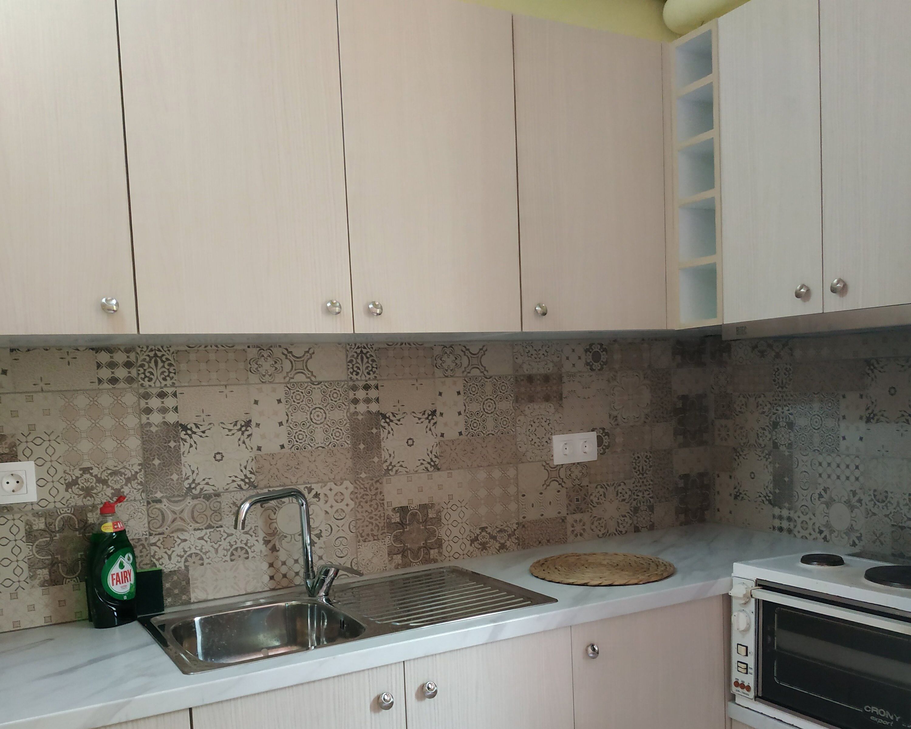 Een keuken met een spoelbak, een fornuis en een decoratieve achterwand.