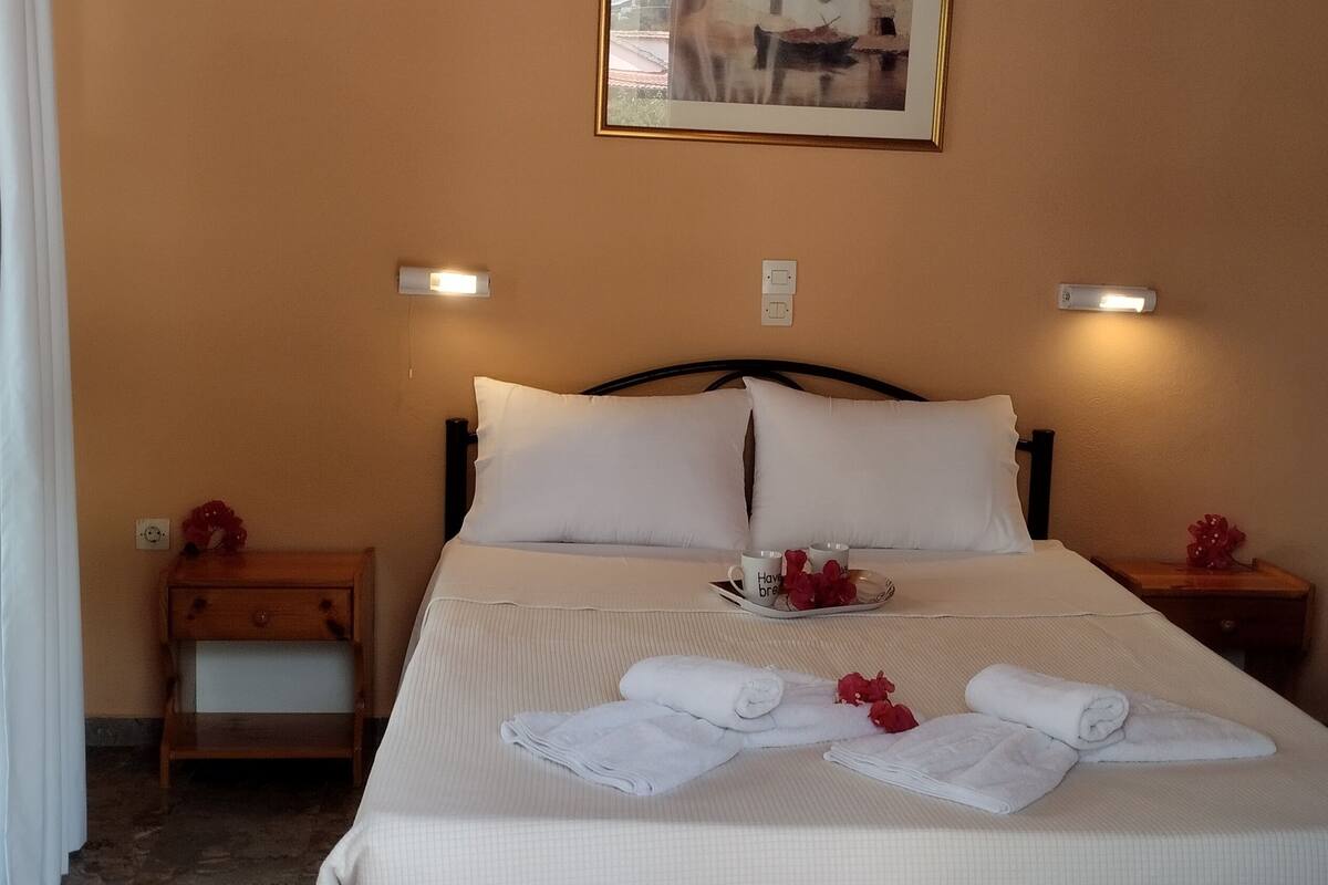 A neatly made bed with white linens, two bedside tables with lamps, and a framed picture on the wall.