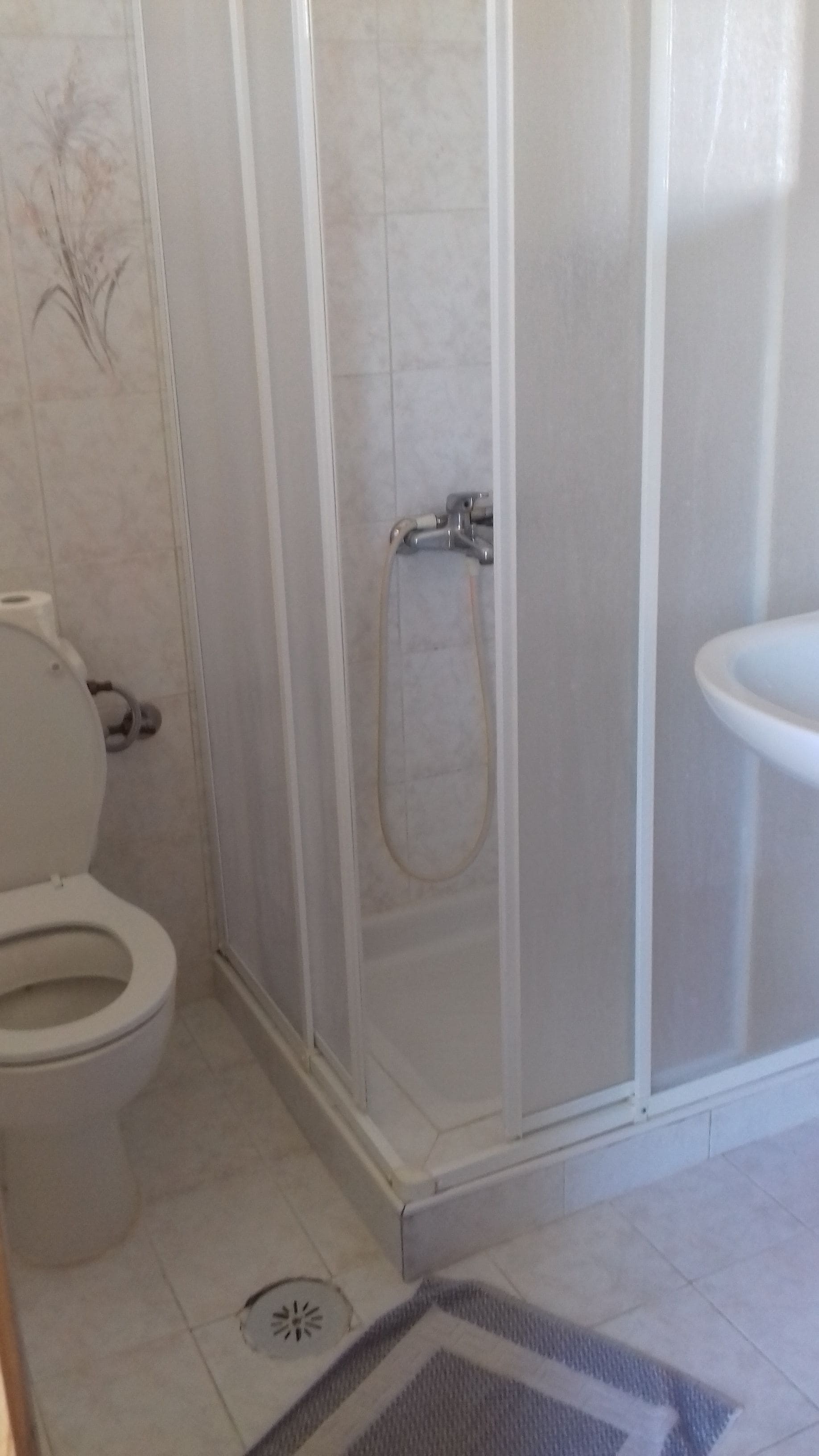 A bathroom with a toilet, shower enclosure, and sink.