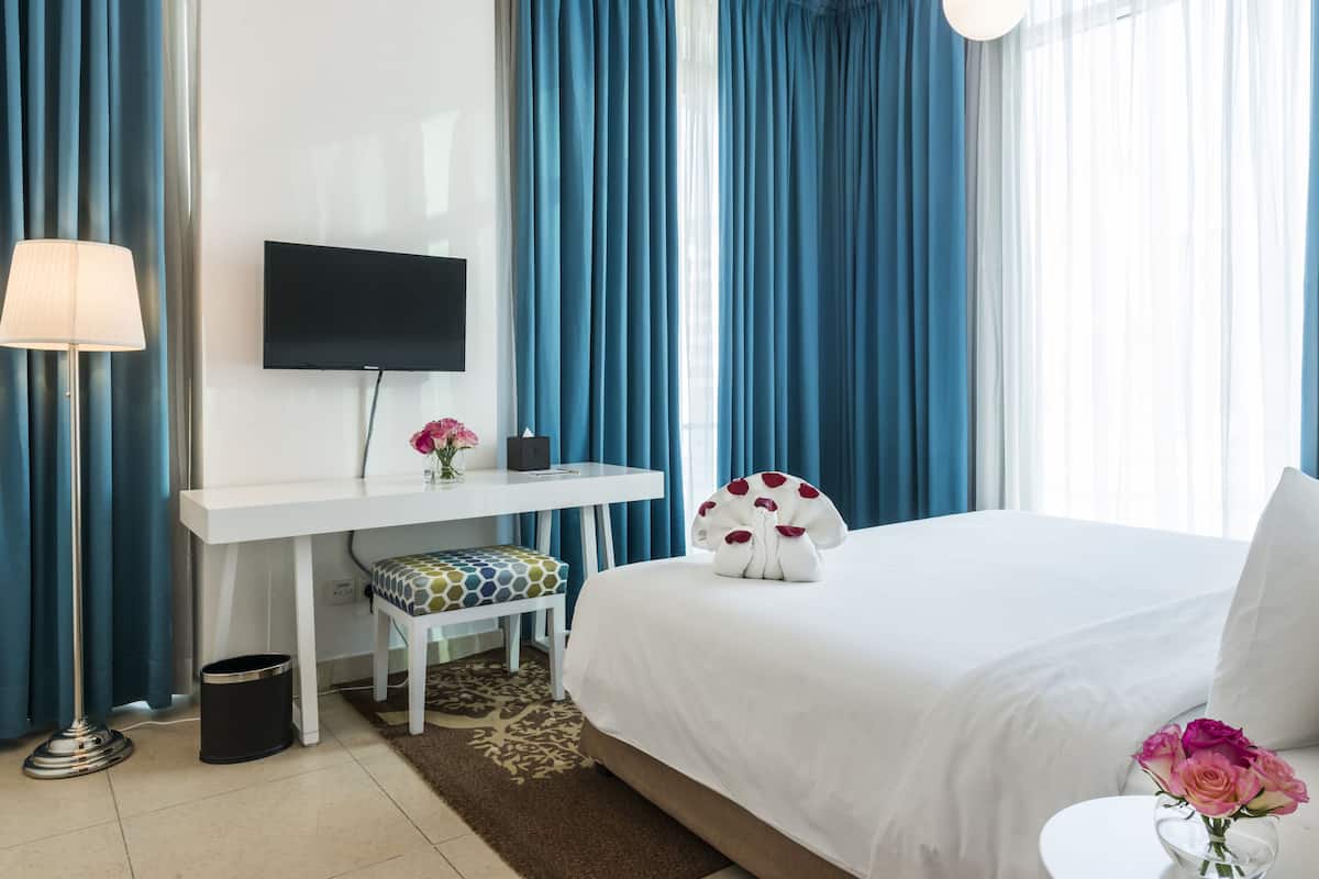 Een hotelkamer met een bed, een bureau, een televisie en een stoel.