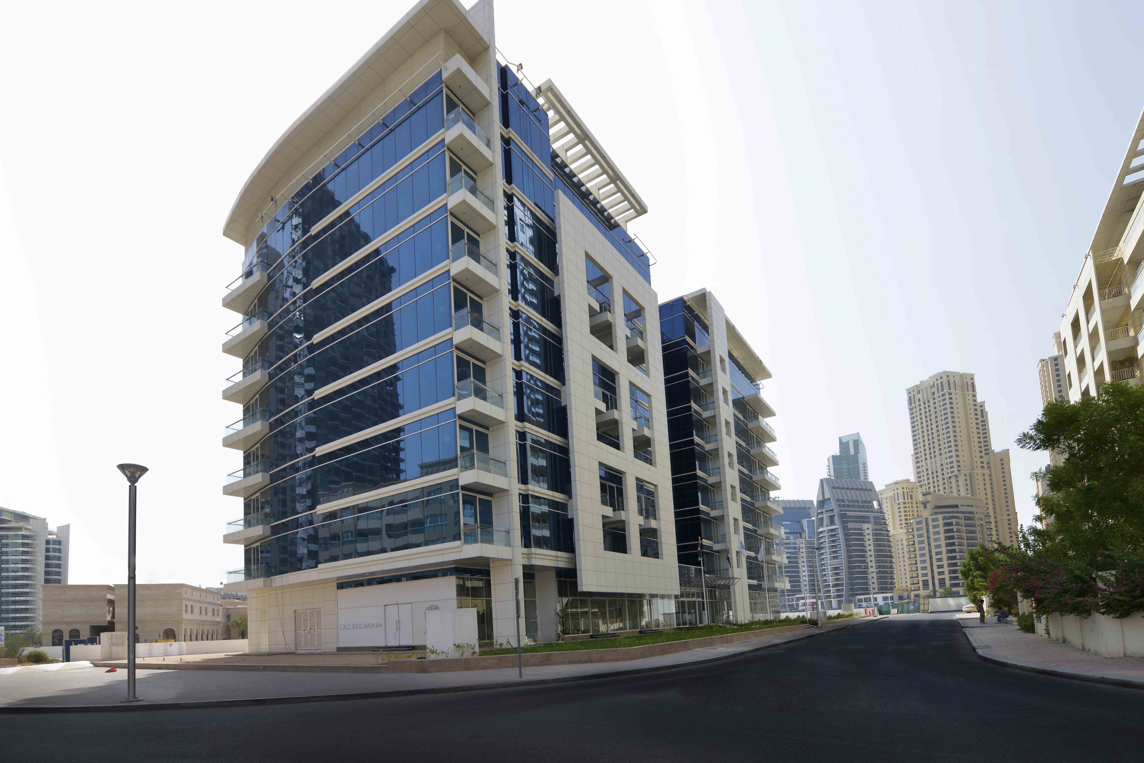 A modern multi-story building with a curved facade, large windows, and a flat roof.