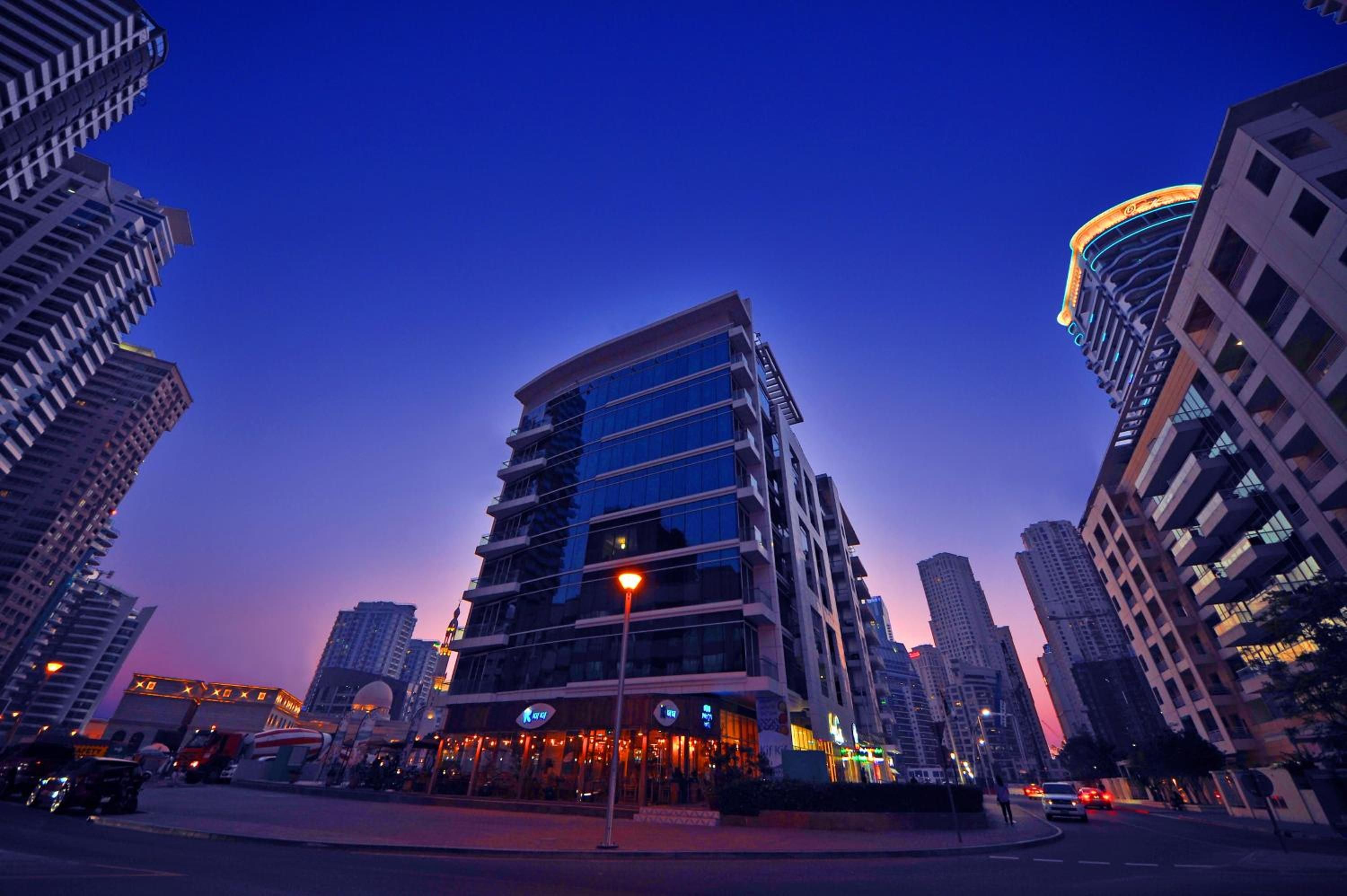 A modern high-rise building with a glass facade, surrounded by other tall buildings.