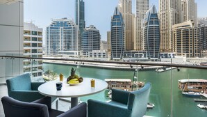 A balcony with a table set for two, overlooking a marina and a city skyline with modern high-rise buildings.