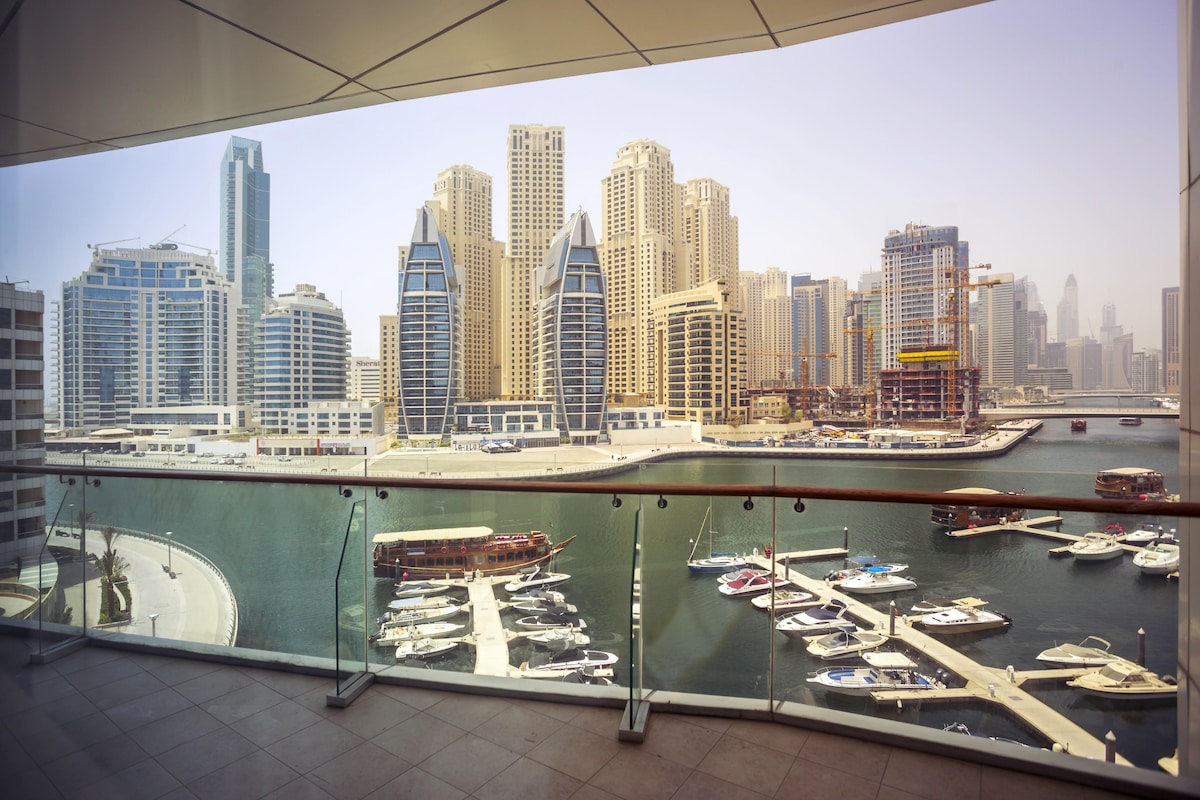 A high-rise building with a marina and boats in the foreground.