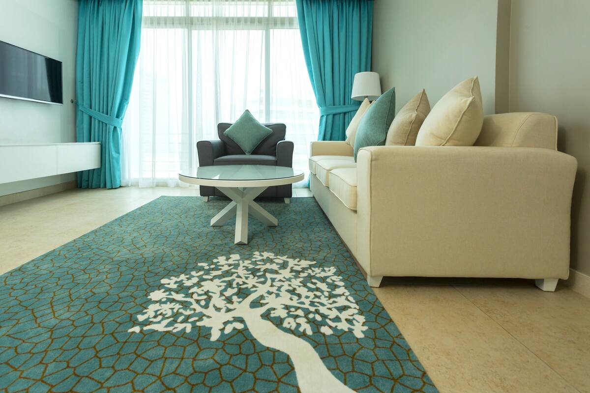 Una sala de estar con sofá, sillón, mesa de centro y televisión en la pared.