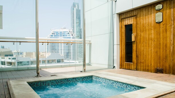 A rooftop pool with a city view, wooden deck, and a sauna area.