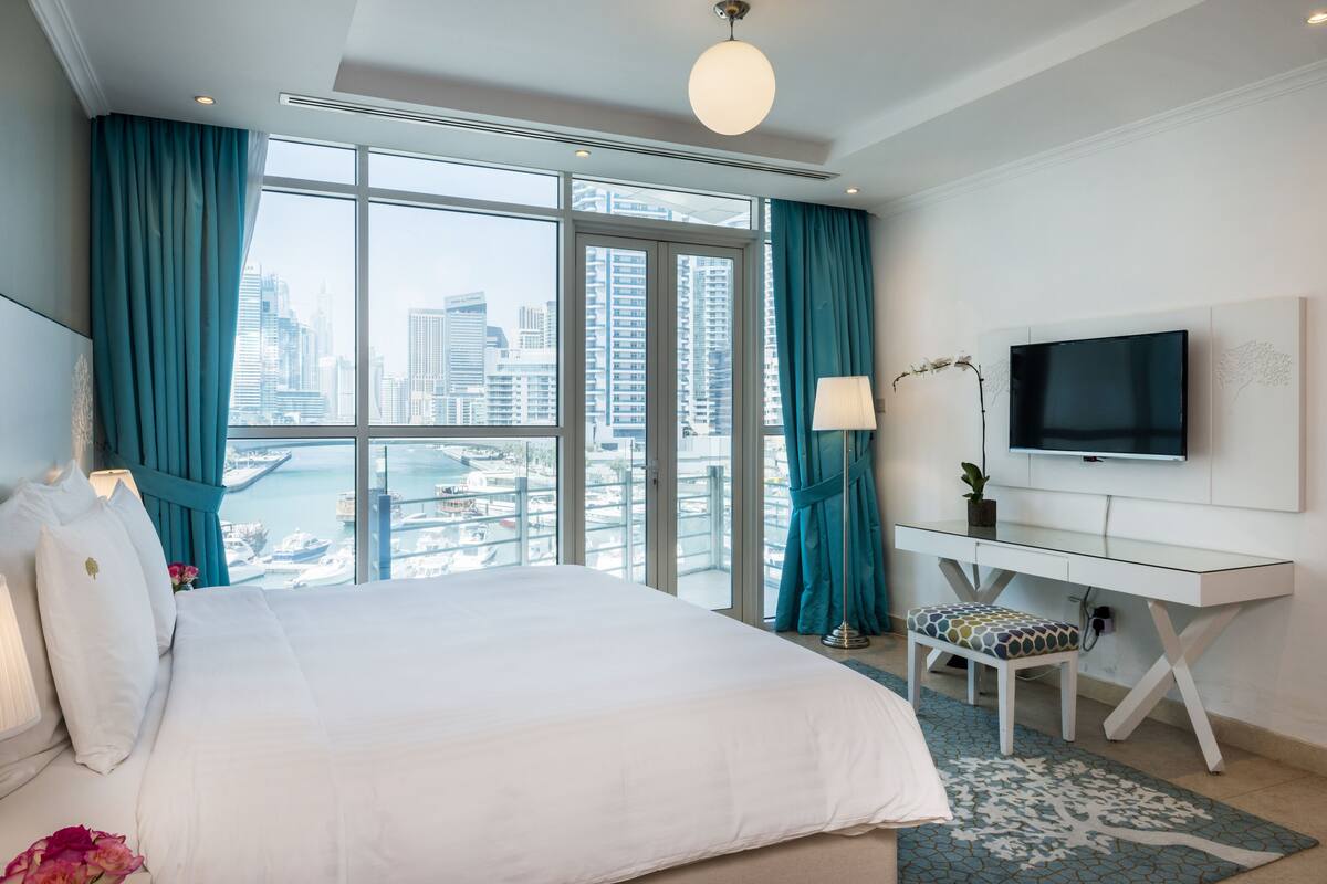Habitación de hotel con una cama grande, un escritorio, un televisor y vistas a la ciudad.