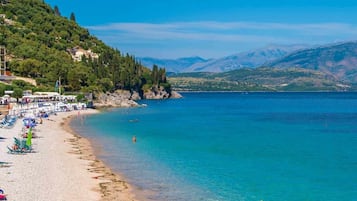 Enjoy a serene beach setting with a wooden pier, lush greenery, and calm waters.