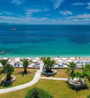 A beach with clear turquoise waters, a row of white umbrellas, and a few palm trees. - Krouzeri Beach Apartments (Corfu)