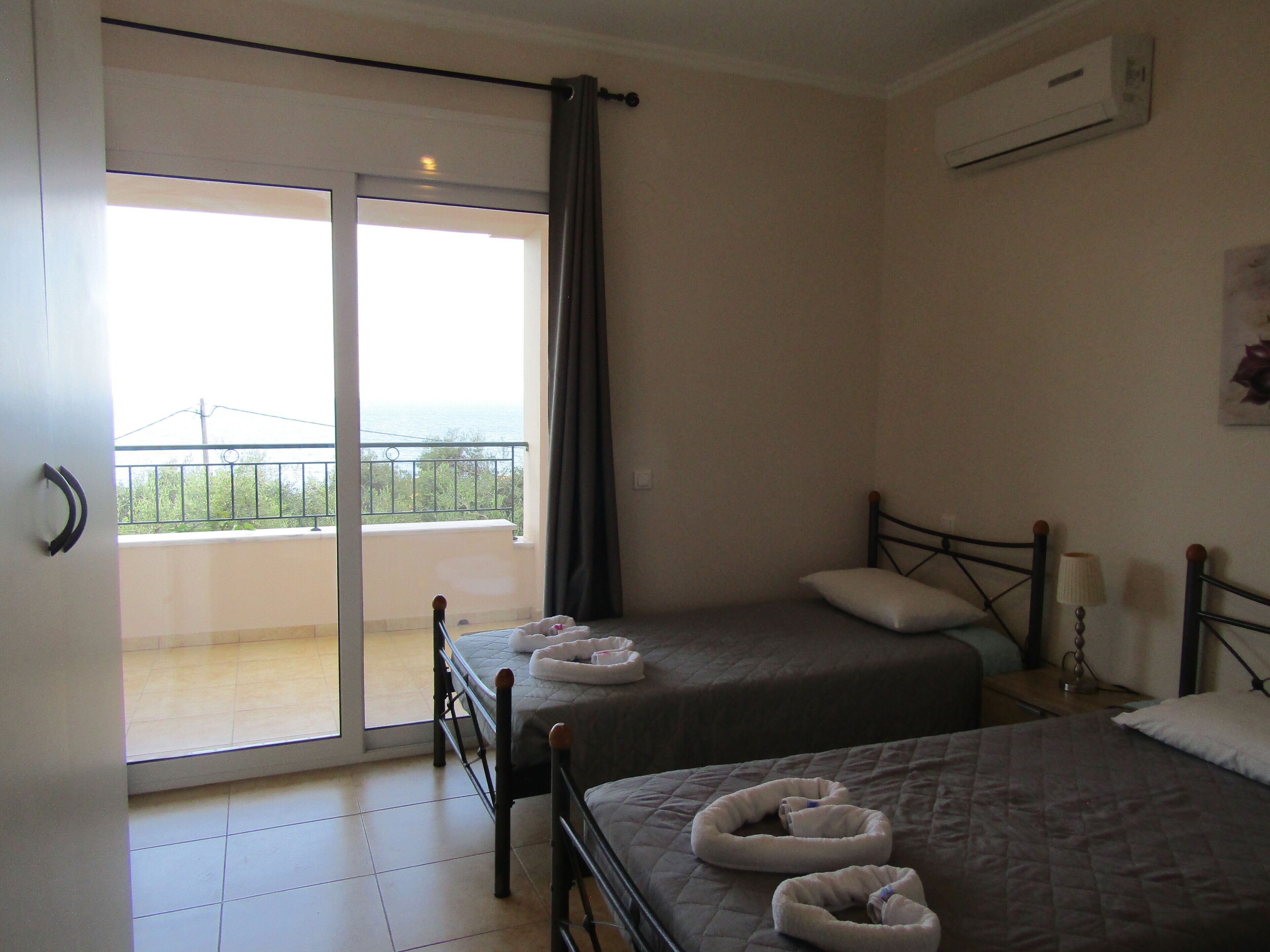 A hotel room with two beds, a balcony, and an air conditioning unit.