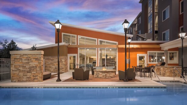 A modern hotel with a swimming pool, outdoor seating, and a stone fireplace.