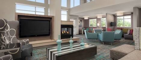 A spacious living room with a large flat-screen TV, a fireplace, and comfortable seating.