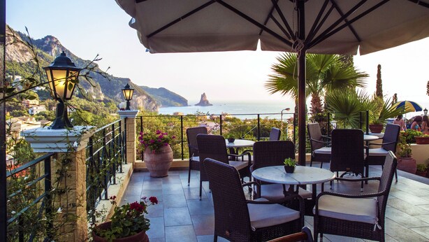 Un patio al aire libre con muebles de mimbre, plantas en macetas y vistas al mar.