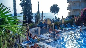 Zona de piscina con sillones reclinables y sombrillas, con vista a un cuerpo de agua.