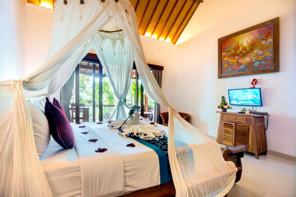 Um quarto com cama de dossel, televisão e um quadro na parede.