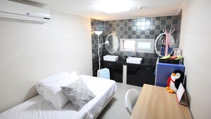 A compact room with a bed, a desk, a chair, a small kitchenette, and a bathroom with a mirror and sink. - Lombard House - Hostel (Seoul)