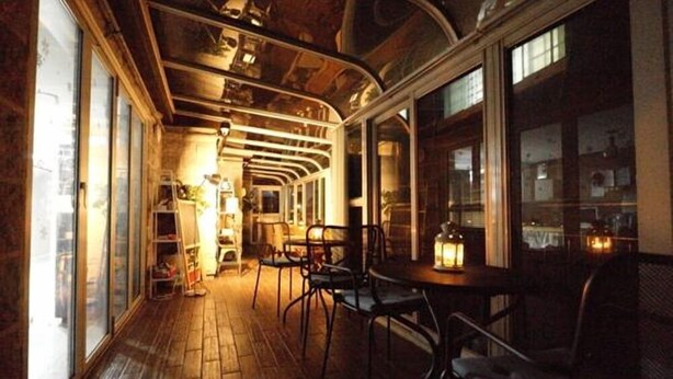 A cozy, dimly lit interior with wooden floors and curved ceiling, featuring a dining area with tables and chairs. - Lombard House - Hostel (Seoul)