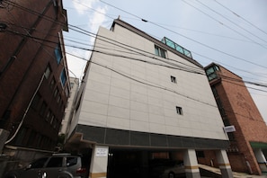 A multi-story building with a tiled facade, a parking garage entrance, and visible power lines.