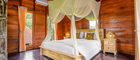 A wooden room with a four-poster bed, a nightstand with a lamp, and a window with curtains.