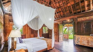 A wooden room with a bed, a nightstand, a lamp, and a wooden cabinet.