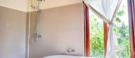 A bathroom with a walk-in shower, a freestanding bathtub, and a window with curtains.