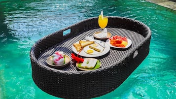A floating dining setup with a drink, toast, and various dishes by a pool.