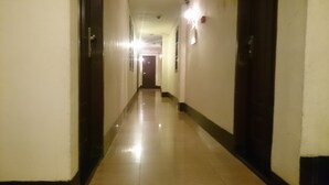 Un lungo e stretto corridoio con porte su entrambi i lati e una fonte di luce in fondo.