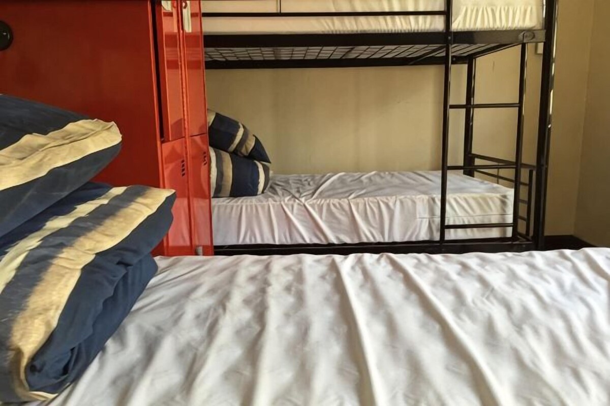 A bunk bed room with a red door, white bedding, and striped pillows.