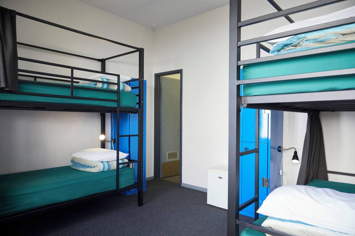 Une chambre avec des lits superposés, un bureau et une porte donnant sur une autre pièce.