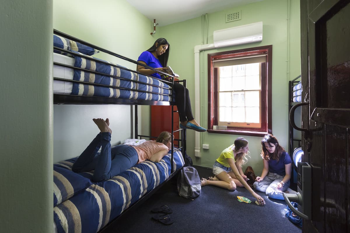 Une chambre de dortoir avec des lits superposés, une fenêtre et une porte.