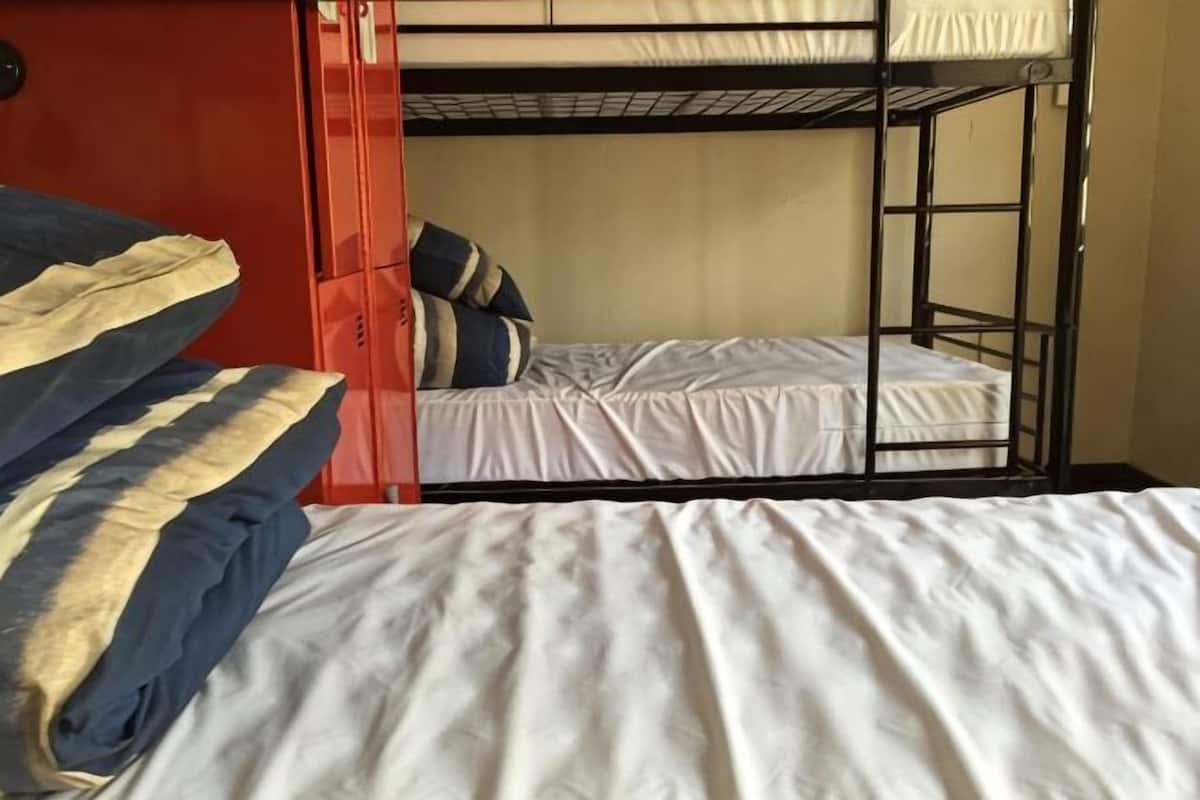 A bunk bed room with a red door, white bedding, and striped pillows.