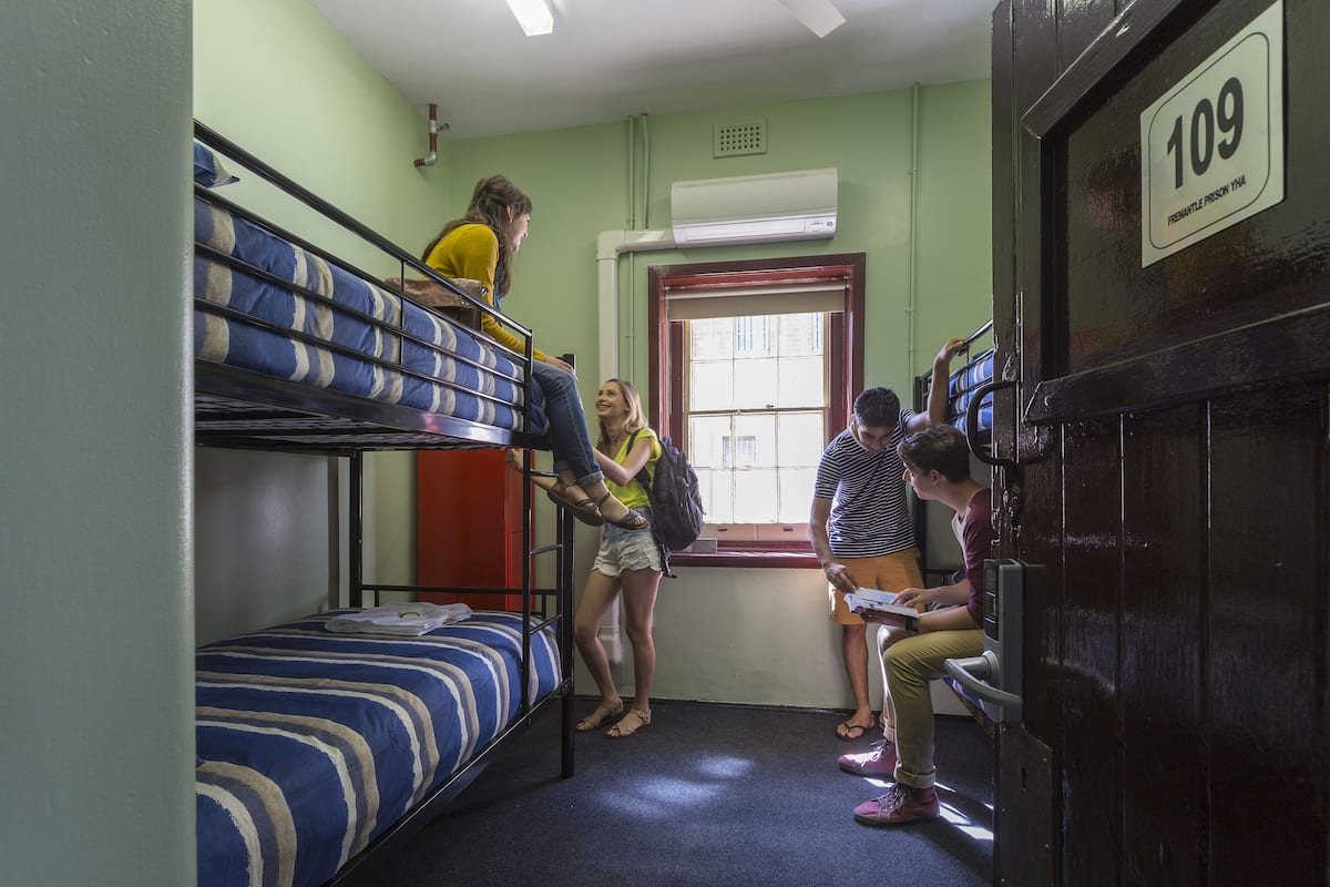 Une chambre de dortoir avec des lits superposés, une fenêtre et une porte portant un numéro.