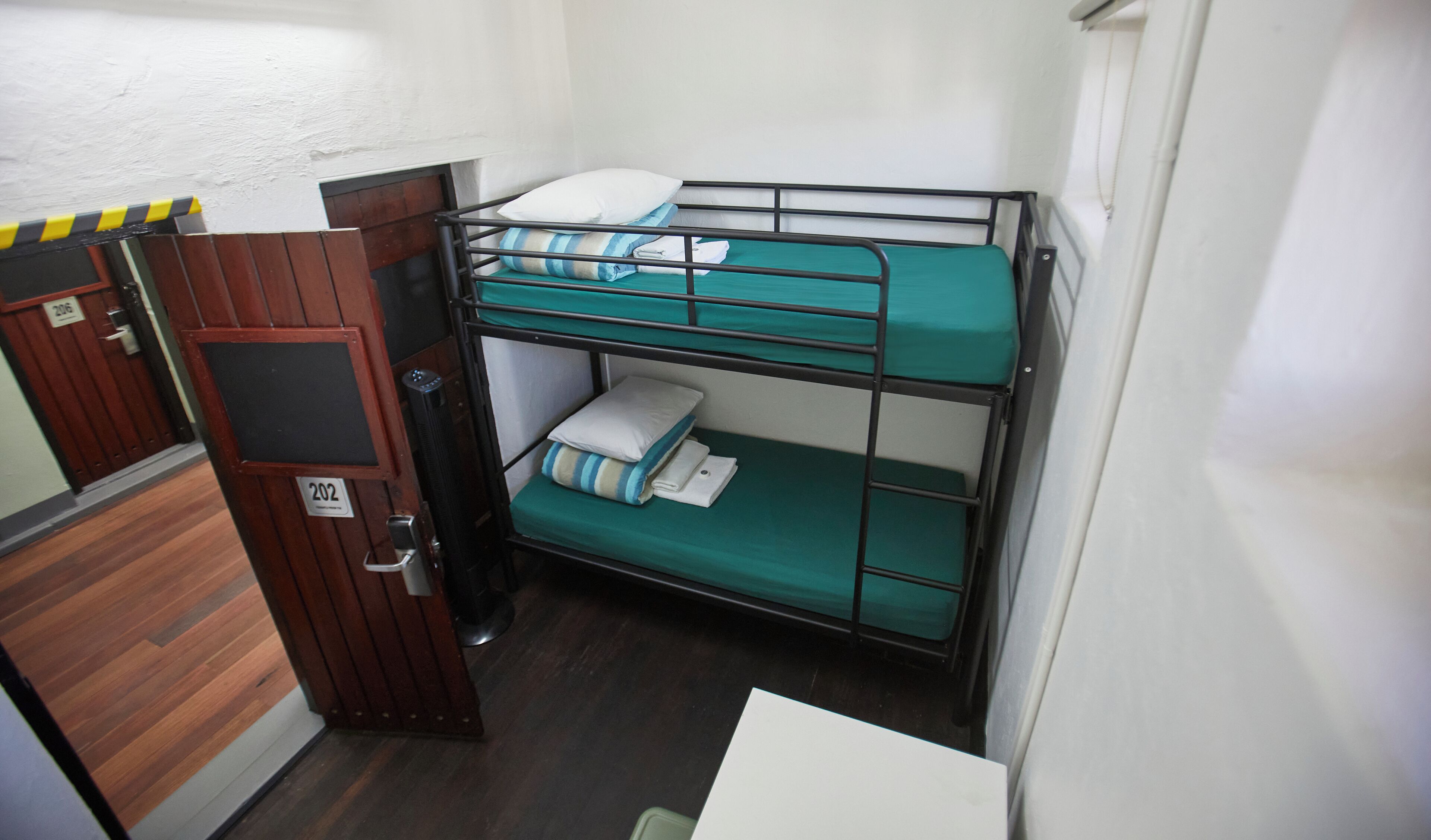 A bunk bed room with a wooden door and a small table.