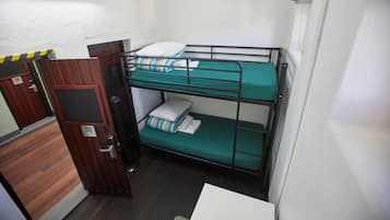 A bunk bed room with a wooden door and a small table.