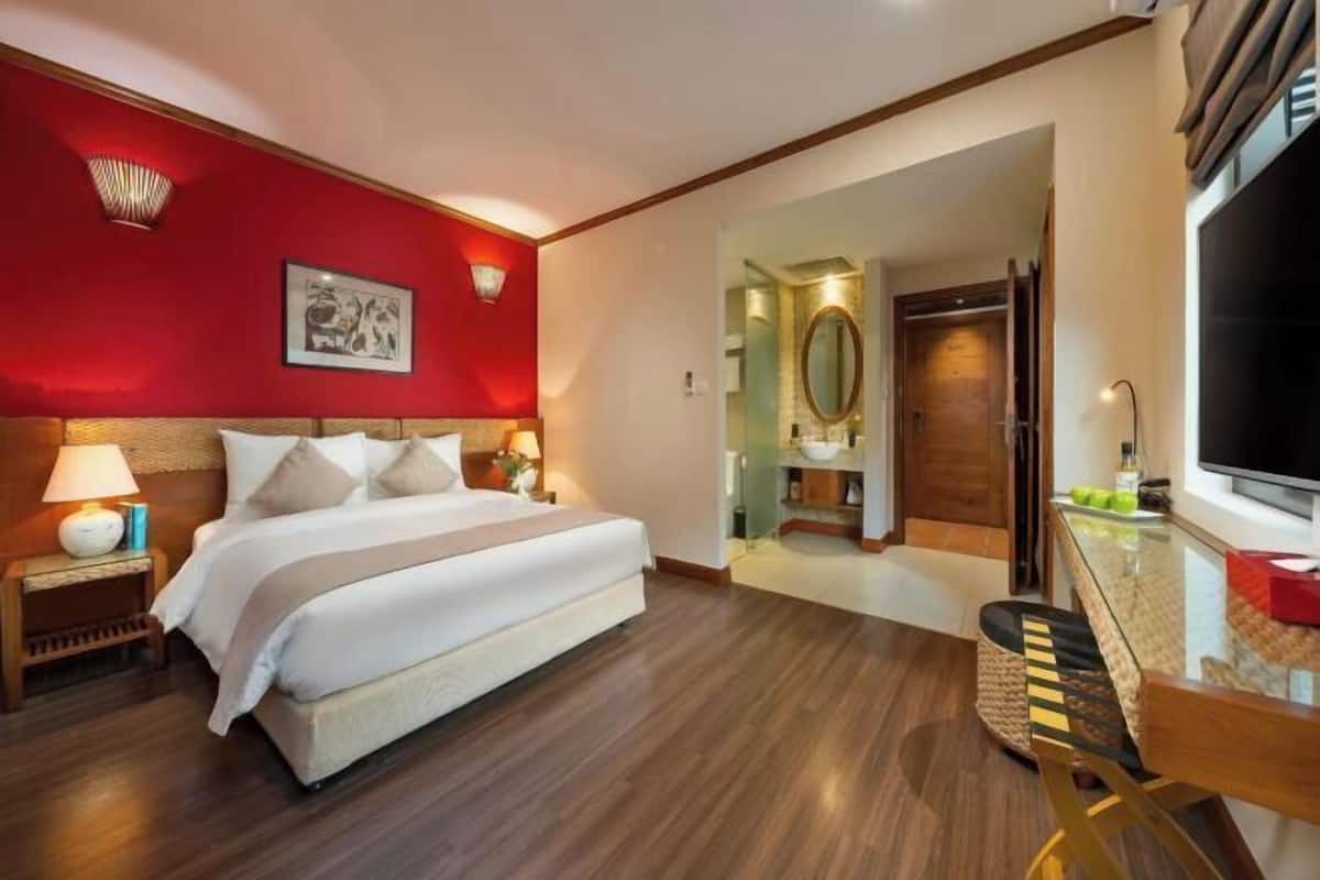 Una habitación de hotel con cama, mesita de noche, l ámpara y televisor.